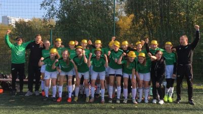 Ett fotbollslag står i två rader. Tjejerna har guldhattar på huvudet och ser glada ut.