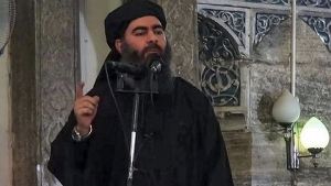 Ääriliike Isisin johtaja Abu Bakr al-Baghdadi puhuu mikrofoniin. Hänellä on yllään musta kaapumainen asu ja päässään musta turbaani.