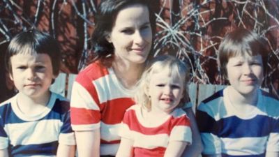 Ett familjeporträtt på en mamma med tre barn. Det yngsta barnet sitter i mammans famn.
