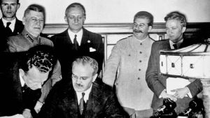 Molotov skriver på nonaggressionspakten den 23 augusti 1939. Bakom honom von Ribbentrop och Stalin. Molotov-Ribbentrop-pakten udnertecknas i Moskva den 23 augusti 1939. Molotov i förgrunden, bakom honom Ribbentrop och Stalin.