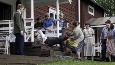 Egon (Ulf Johansson) förs hastigt hem mitt i slåttern. Hustrun Ester (Anci Holm) hjälper till. T v sonen Orvar (Arttu Flén). Foto: Johanna Överfors