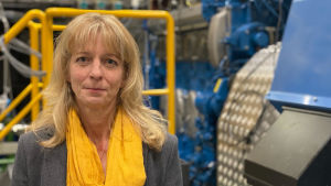 Kirsi Spoof-Tuomi har forskat i hur man i Sverige och Norge lyckats få lönsamhet i produktionen av flytande biogas. Blond kvinna med gul halsduk står i forskningslaboratorium.