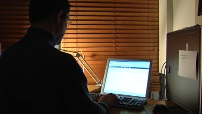 Man sitter framför dator