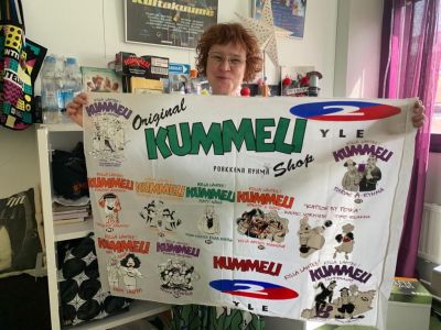 Nainen näyttää kangasta, jossa on Kummeli-painatuksia.