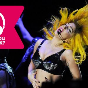 Lady Gaga blundar, är iklädd BH, har trådlös mikrofon vid munnen och slänger med huvudet bakåt, så håret står på ända.