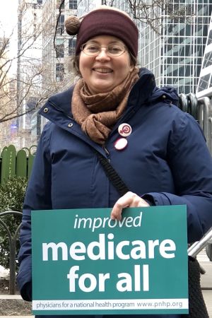 Jenny Brown, feministisk författare i New York Jenny Brown vid sidan av demonstration bland New Yorks skyskrapor, med plakakt om Medicare för alla