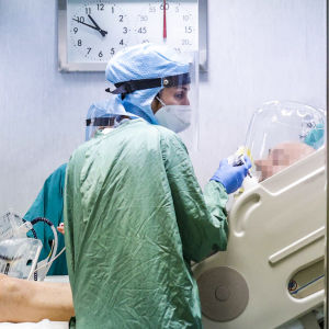 En grupp sjukskötare står vid en patients säng på en coronaintensivavdelning.