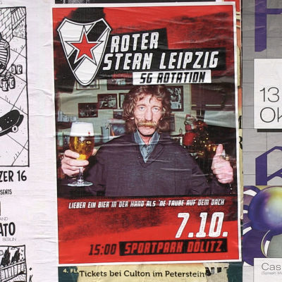 En mustaschprydd man med en öl i handen på en reklamaffisch.