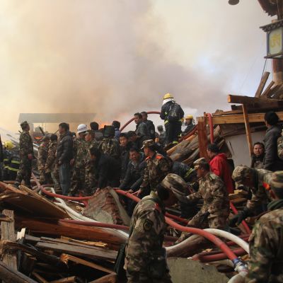 Sotilaita ja muita henkilöitä tulipalon raunioissa.