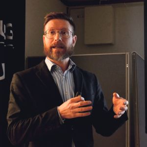 Nikolas Salomaa säger att det var tufft att bli indragen i de politiska diskussionerna om Salutorgets värmesystem, men att han är lättad att det nu är över. en man i kavaj och skägg håller en presentation
