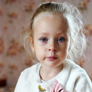 Vaaleahiuksinen ukrainalainen pikkutyttö katsoo suoraan kameraan. 