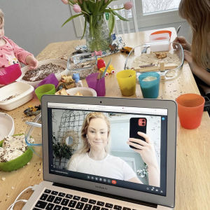En bild på mamma Carola Nordberg som är inloggad i ett videomöte. Bakom datorskärmen sitter två barn vid matbordet och leker med varsin upptäckarlåda. Bordet är fullt av riskorn som fallit från lådorna.