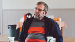 Karl-Göran Karlsson minns hur president Koivisto hade bråttom att genast byta kostymen till arbetskläder när han kom till Hemmings i Ingå. En äldre man med glasögon skägg sitter bakom ett långbord.