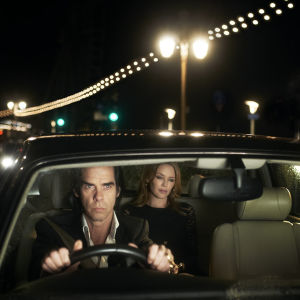 Nick Cave ajaa autoa, Kylie Minougue istuu kyydissä. Kuva dokumenttielokuvasta Nick Cave: 20 000 päivää maan päällä.