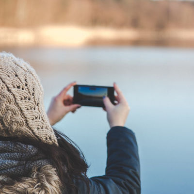 Tjej i vinterkläder som tar ett foto med en smarttelefon.