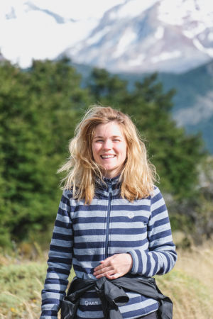 Trots jobb som digital nomad är det viktigt att också hinna njuta av resan. En kvinna iklädd en randig fleecetröja. Hennes blonda hår är rufsigt och hon skrattar stort. I bakgrunden syns träd och berg.