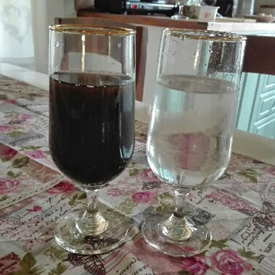 Två glas med vatten, varav det ena har svart vatten.