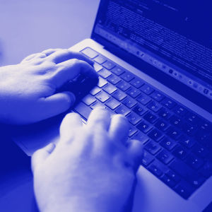 Miehen kädet kannettavan tietokoneen näppäimistöllä.