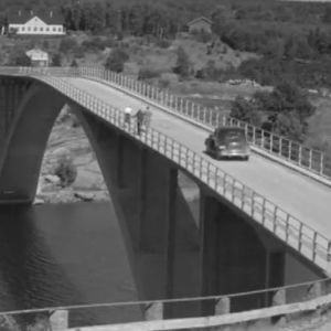 Vanha auto ajaa sillalla, jonka alla virtaa joki.