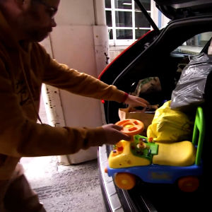 En man drar en leksaksbil ur en fullastad bilbaklucka.