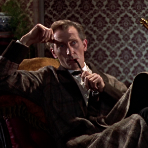 Sherlock Holmes (näyttelijä Peter Cushing) polttaa piippua nojatuolissa ja katsoo kurtistettujen kulmiensa alta. Kuva elokuvasta Baskervillen koira.