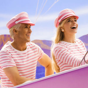 Vaaleanpunaisiin merikapteeniasuihin pukeutuneet mies ja nainen moottoriveneen kyydissä