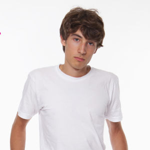 en pojke i vit t-skjorta mot en vit bakgrund som står och ser olrolig och ledsen ut