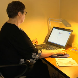 Ingrid Hollmérus-Nilsson sitter framför en dator. 