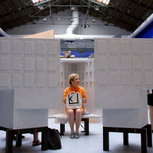 Minna Joenniemi istuu pienoismallin sisällä penkillä Venetsian biennaalissa