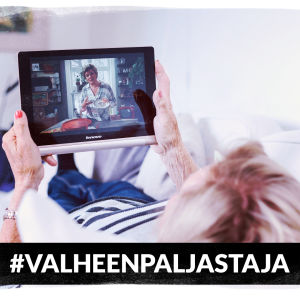 Eläkeikäinen nainen makoilee sohvalla katsoen tablettia. Kuvassa teksti Valheenpaljastaja.