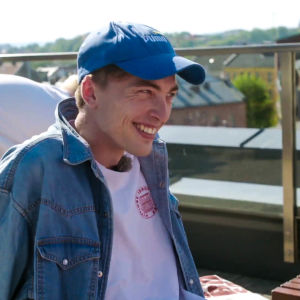 Markus Langen blir inte sur om han får en snoppbild. Markus Langen ler finurligt med keps på huvudet på en takterrass.