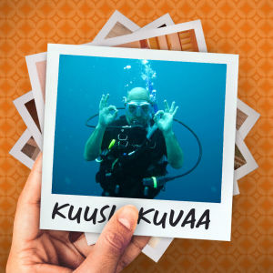 Mies sukellusvarusteissa veden alla näyttää kameralle molemmilla käsillään ok-merkkiä.