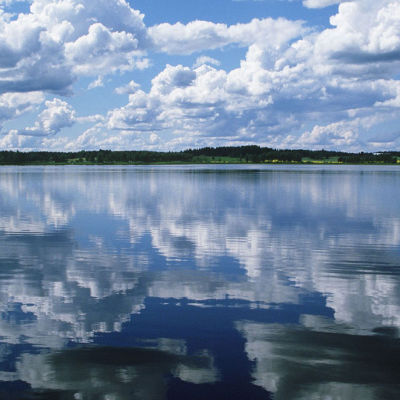 Pilvet kuvastuvat tyyneen järven pintaan.