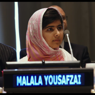 Malala Yousafzai med namnskylten framför sig i samband med en kongress