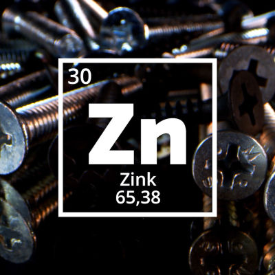 Symbolen för Zink, Zn. I bakgrunden skruvar av zink.  