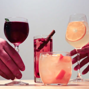 Neljä cocktailia, joita kaksi kättä ottamassa.