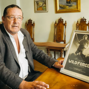 Lars Backlund visar upp filmplanschen för filmen som aldrig blev av. Man med inramad Wild Force filmposter