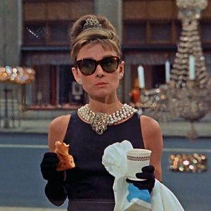 Audrey Hepburn syö aamiaistaan kultasepänliike Tiffanyn näyteikkunan ääressä elokuvassa Aamiainen Tiffanylla