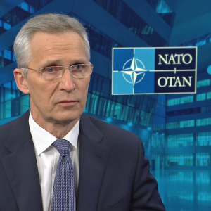 En man i kostym och slips i en tv-studio. På väggen Natos emblem med texten NATO | OTAN.