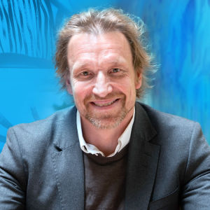Kuvassa on Marco Mäkinen sinisävyiden taustan edessä