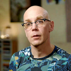 Andreas Forsman sitter med glasögon och ljusblå t-skjorta och tänker
