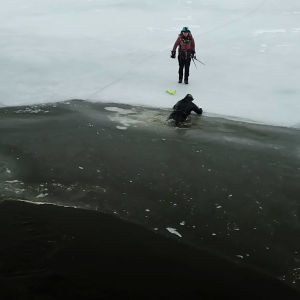 En man har gått genom isen, han har tryckt isdubbarna i isen och försöker ta sig upp.