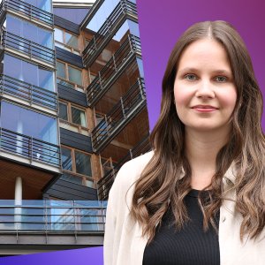 Laura Törnroos står framför en bild på ett flervåningshus.