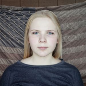 Kuva nuoresta naisesta Yhdysvaltain lipun edessä.