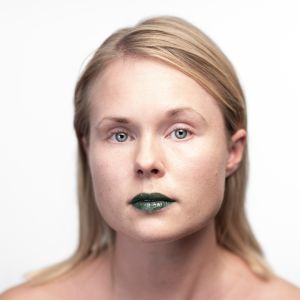 Suoraan kameraan katsovan naisen huulet on maalattu vihreällä.