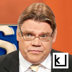 Timo Soini etualalla, hänen takanaan iso PS-pinssi, jonka takaa kurkistaa Jussi Halla-aho.