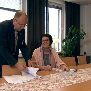 Styrelsemedlemmen Marianne Buss justerar protokoll hos verksamhetsledare Markku Suoranta vid Österbottens cancerförening man och kvinna tittar i papper