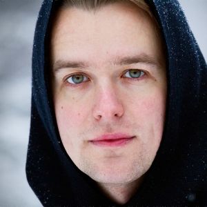 Lauluntekijä Topi Saha katsoo kameraan huppu päässään.