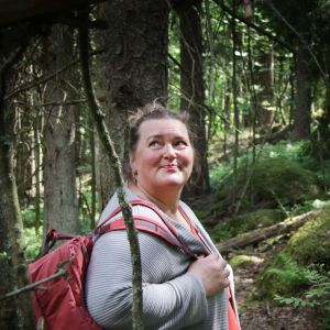psykologi Liisa Uusitalo-Arola metsäretkellä reppu selässä iloisen näköisenä