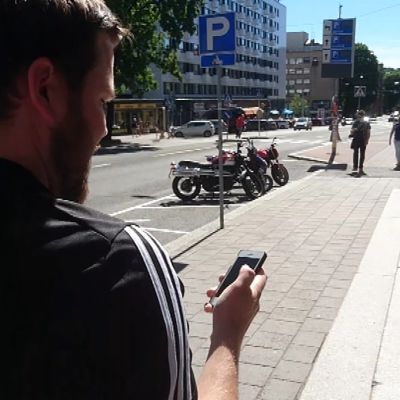 Mies kävelee ja katsoo puhelintaan.